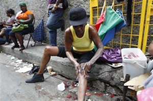 In this photo taken Feb. 15, 2011, a woman applies skin lightening cream to her legs as she sits on a curb in downtown Kingston, Jamaica. People around the world often try to alter their skin color, using tanning salons or dyes to darken it or other chemicals to lighten it. In the slums of Jamaica, doctors say the skin lightening phenomenon has reached dangerous proportions. (AP Photo/Caterina Werner)